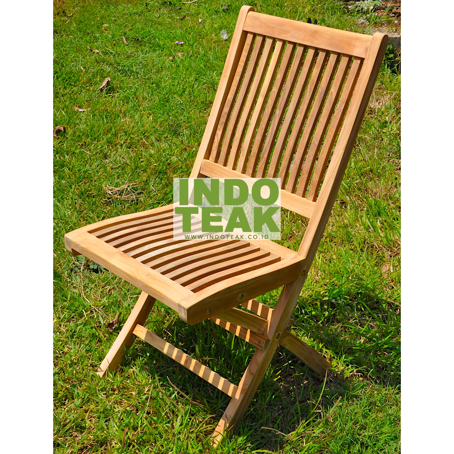Premium solid teak folding chair on green grass field by Indoteak Indonesia, luxury teak outdoor garden furniture manufacturer