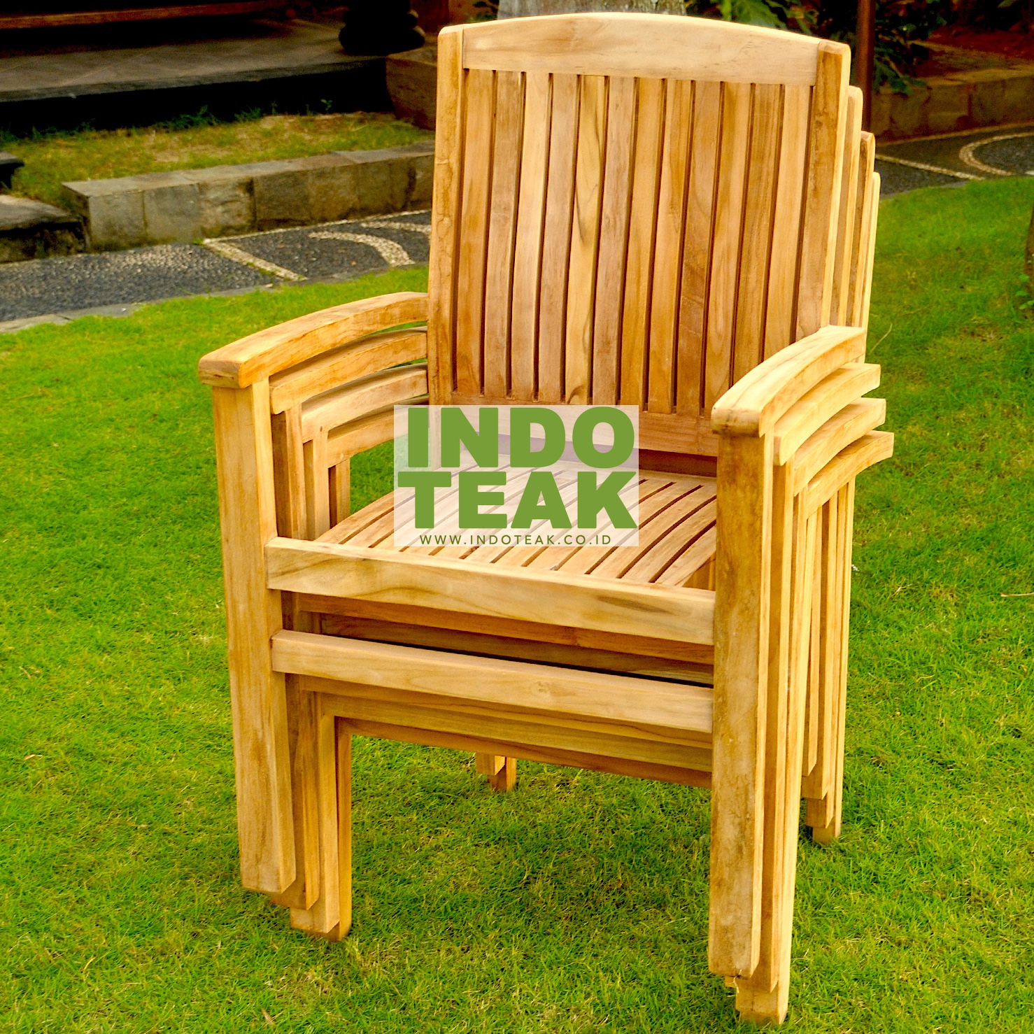 Premium solid teak stacking armchair stacked on green lawn by CV. Indoteak Sukses Makmur, Indonesian outdoor furniture exporter